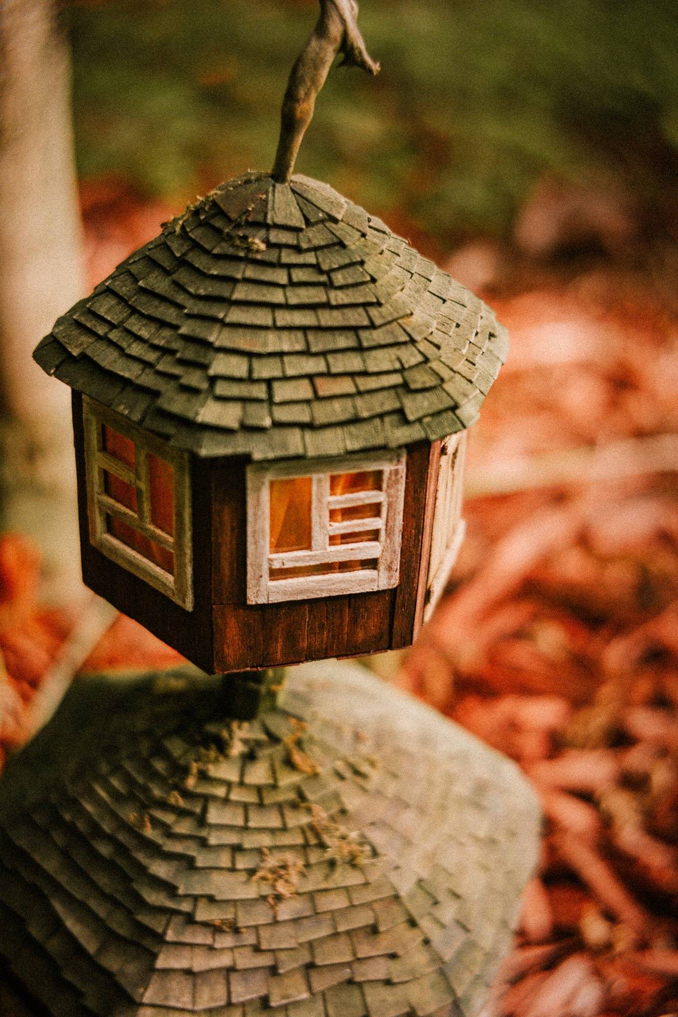 A two-tier wooden tower with shingled conical roofs and white-framed windows lit warm from within