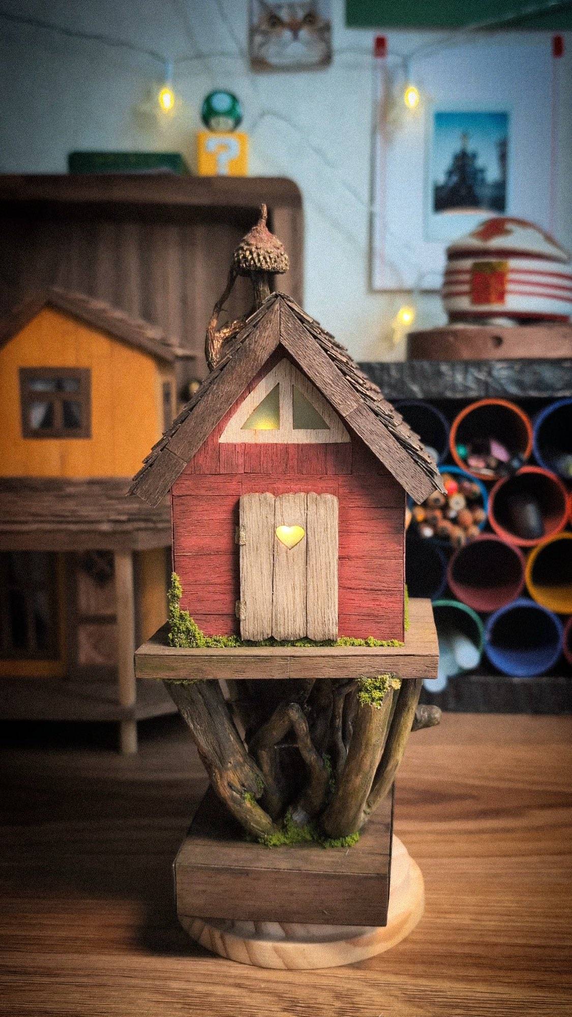 The finished cottage in the workshop, painted red with its window lit