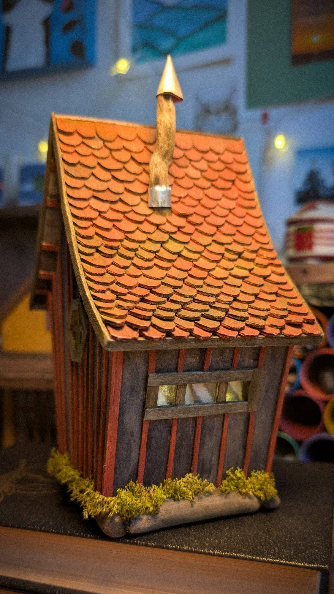 The cottage on the workbench, tin chimney cap catching the light